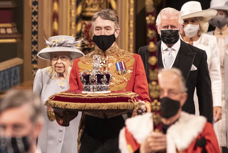 Britain’s Queen Elizabeth II and Britain’s Prince Charles, Prince of Wales walk behind the Imperial State Crown as they process through the Royal Gallery, before the Queen’s Speech, during the State Opening of Parliament at the Houses of Parliament in London on May 11, 2021, which is taking place with a reduced capacity due to Covid-19 restrictions. – The State Opening of Parliament is where Queen Elizabeth II performs her ceremonial duty of informing parliament about the government’s agenda for the coming year in a Queen’s Speech. The Queen is escorted out of the House of Lords by Prince Charles and led by the imperial state crown following her speech during the state opening of Parliament. Due to the ongoing Corona pandemic guests in the royal gallery were limited and socially distanced.